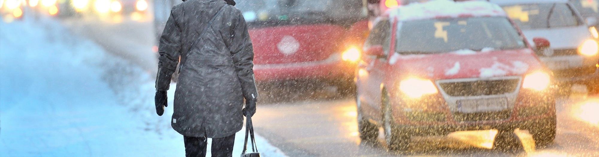 Commuter walking past traffic in a heavy snowstorm
