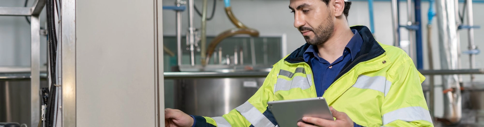 Engineer in hi-vis using a tablet in a plant room