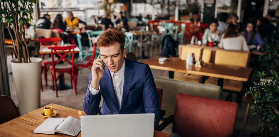 Business man using laptop and phone at cafe