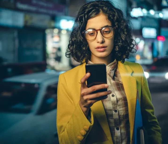 Business woman using phone on a busy road at night