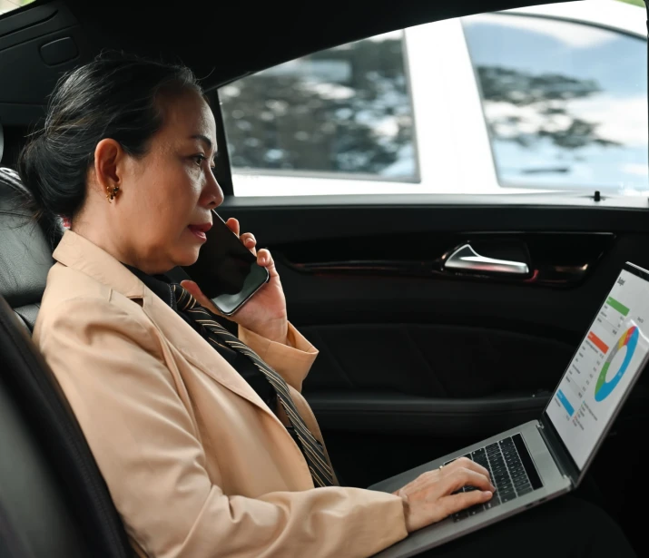 Business women on the phone and on laptop in a car
