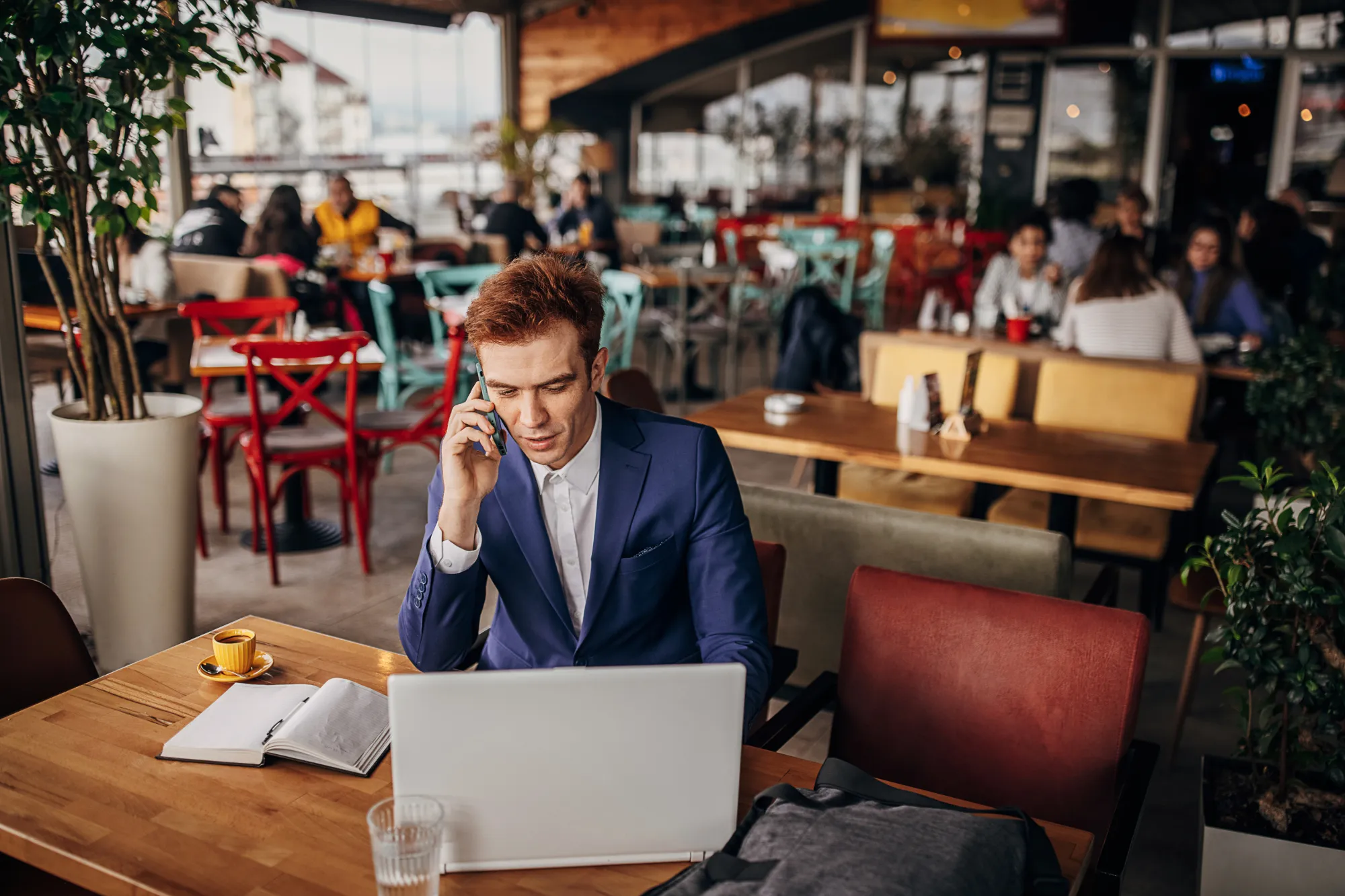Business man using laptop and phone at cafe